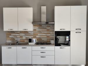 a kitchen with white cabinets and a black microwave at Casa Vacanza Magnolia in Tollo