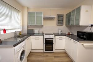 a kitchen with white cabinets and a sink and a dishwasher at Edwards House, Sleeps 5 in 3 bedrooms, Bath Road, Cheltenham in Cheltenham