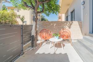 un patio con 2 sedie, un tavolo e un albero di Leopardi Design with 2 bathrooms ad Alba Adriatica