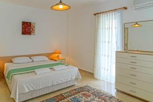 a white bedroom with a bed and a dresser at Mona Apart with sea platform in Yarim Adası