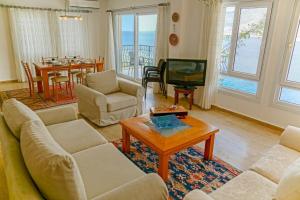 a living room with a couch and a tv and a table at Mona Apart with sea platform in Yarim Adası