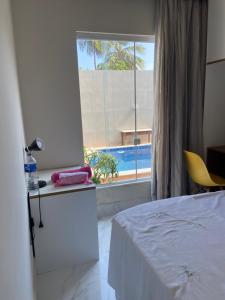 a bedroom with a bed and a window with a pool at Itapuã Beach II Espaço climatizado com piscina privativa e área gourmet! in Salvador