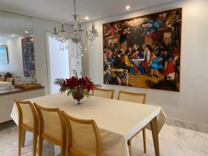 a dining room with a table and a painting on the wall at Itapuã Beach II Espaço climatizado com piscina privativa e área gourmet! in Salvador