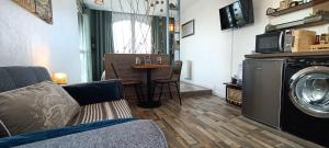 a living room with a washing machine and a table at Le Sémaphore - studio climatisé, grande terrasse vue mer - parking, wifi in La Grande Motte