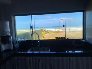 a kitchen with a view of the beach through a window at Suites Frente ao Mar in Prado