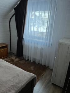 a bedroom with a bed and a large window at Незабутні Карпати in Vorokhta