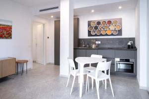 een keuken met een witte tafel en witte stoelen bij Appartamento Guglielmo in Oristano