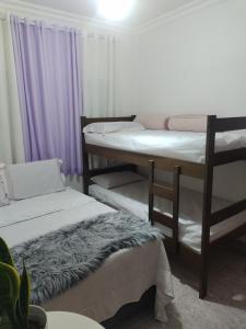 a room with three bunk beds and purple curtains at Casa de campo rocha in Ribeirão Pires