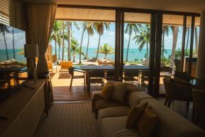 a living room with a couch and a view of the ocean at Casa Believe Milagres in Passo de Camarajibe