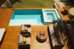 a wooden deck with a pool with chairs and a table at Casa Believe Milagres in Passo de Camarajibe +5 photos