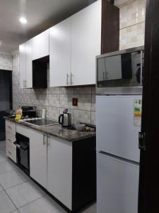 a kitchen with white cabinets and a white refrigerator at DBright Lodge in Pretoria