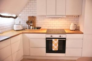 a kitchen with white cabinets and a stove top oven at Visby innerstad St Hans in Visby