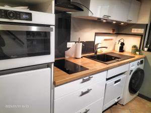 een keuken met een spoelbak en een fornuis bij Au bord du vieux Moulin - près de Bordeaux in Mérignac