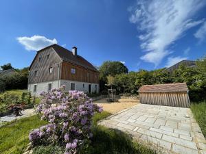 a barn with purple flowers in front of a yard at LandQuartier - La Primera in Dürrröhrsdorf