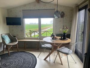 a dining room with a table and chairs and a window at In Daaldersk Plakje in Deinum