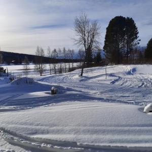 a snow covered field with a road in the distance at Apartment Suutarintie - Authentic Lappish experience by the River in Rovaniemi
