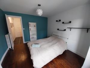 a bedroom with a white bed and a blue wall at Le Flow d'Issoire - Charmant appartement avec terrasse in Issoire