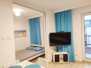 lustro w pokoju z łóżkiem i telewizorem w obiekcie Apartament Kapitalny przy porcie w Kołobrzegu z rowerownią i placem zabaw w Kołobrzegu