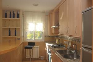 cocina con armarios de madera, fregadero y ventana en Apartaments Villa Conchi, en Sitges