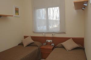 two beds in a room with a window at Apartaments Villa Conchi in Sitges