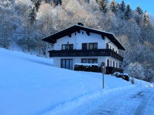 a house on a snow covered hill with a road at Appartement Maria Theresia in Hopfgarten im Brixental +10 photos