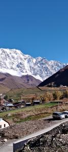 a car parked on the side of a road with a snow covered mountain at Family Hotel Twins in Ushguli