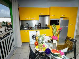 a kitchen with yellow cabinets and a table with fruit on it at Appartement vue mer situé aux Trois-Ilets, Martinique in Les Trois-Îlets
