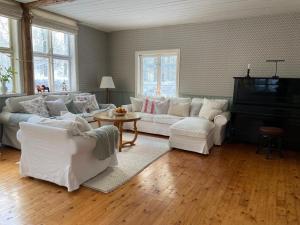 a living room with white couches and a piano at Torsholma Skolhus in Hallaryd