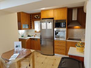 a kitchen with wooden cabinets and a stainless steel refrigerator at KTHMA "Ν" Πέτρινη Μεζονέτα in Ververáton
