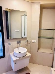 a white bathroom with a sink and a mirror at Rose Room in Nagpur +3 photos