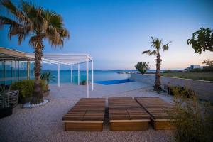 a picnic table with palm trees and a view of the ocean at Arcadia - Beach villa n.1 in Privlaka