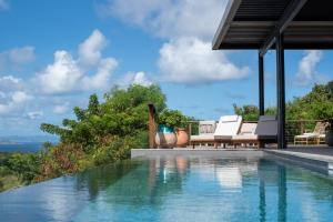 a swimming pool with two lounge chairs next to a house at Domaine de Sweet Hill - 4 villas et 2 studios in Saint Barthelemy