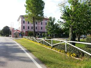 a white fence in front of a pink building at Dogana Vecchia - Hotel & Residence B&B Ristorante & Pizzeria in Trivignano Udinese