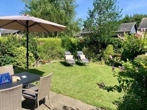 a patio with a table and chairs and an umbrella at Bungalow in dune area of Sint Maartenszee in Sint Maartenszee