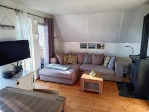 a living room with a couch and a tv at Cozy holiday home in Sint Maartenszee in Sint Maartenszee