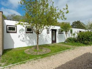 a white house with a tree in the yard at Furnished bungalow near beach in Sint Maartenszee