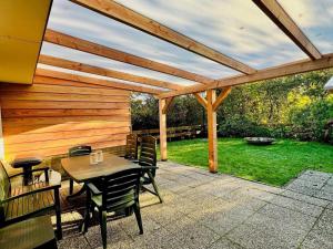 a patio with a wooden pergola and a table and chairs at Bungalow in Sint Maartenszee near beach in Sint Maartenszee