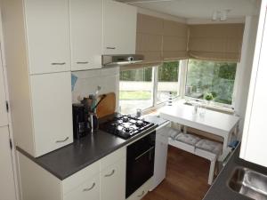 a kitchen with white cabinets and a stove top oven at Bungalow in Sint Maartenszee near beach in Sint Maartenszee
