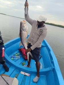 a man holding a fish in a blue boat at La Case Sauvage in Diana