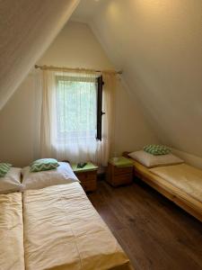 two beds in a attic room with a window at Czarna Jagoda in Czarna Góra
