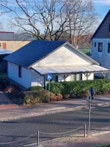 a white building with a blue roof next to a street at Ferienhaus Auenland in Brunsbüttel