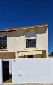 ein weißer Zaun vor einem Haus in der Unterkunft Casa en El Pedroso de tres habitaciones in El Pedroso