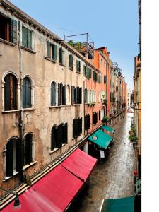 un callejón con edificios y toldo rojo en Botteri Palace Apartments, en Venecia