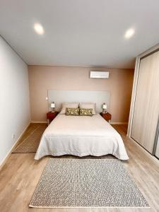 Un dormitorio con una gran cama blanca con dos mesitas de noche. en Nina da Nazare, en Nazaré