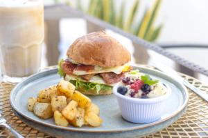 a plate with a sandwich and potatoes and a drink at Casa Ramona in Flores