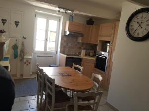 a kitchen with a wooden table and a clock on the wall at Maison Provençale in Bauduen