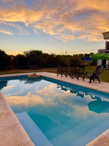 a swimming pool with two chairs and a table at Puesta de Sol Casa Quinta in Azul