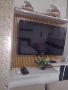 una grande TV a schermo piatto seduta su un muro di Loft microcasa em Altos da Cidade - perto de tudo a Bauru
