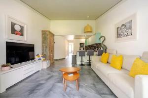 a living room with a white couch and yellow pillows at Scarlet's Place - 1 bed Victory Village Quinta Do Lago - beach, nature, lakes in Quinta do Lago