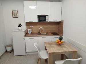 a small kitchen with a wooden table and a sink at Apartmani - sobe Ćosić in Neum